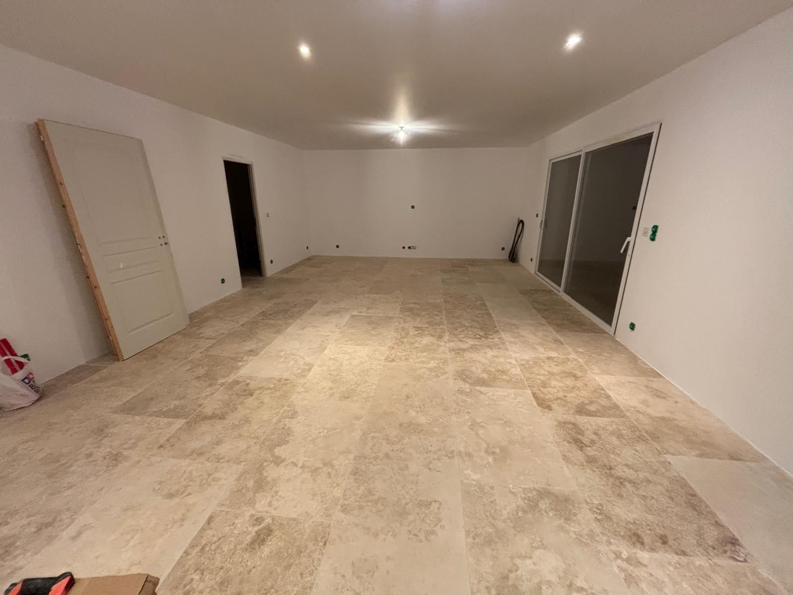 Grande pièce avec carrelage en travertin posé