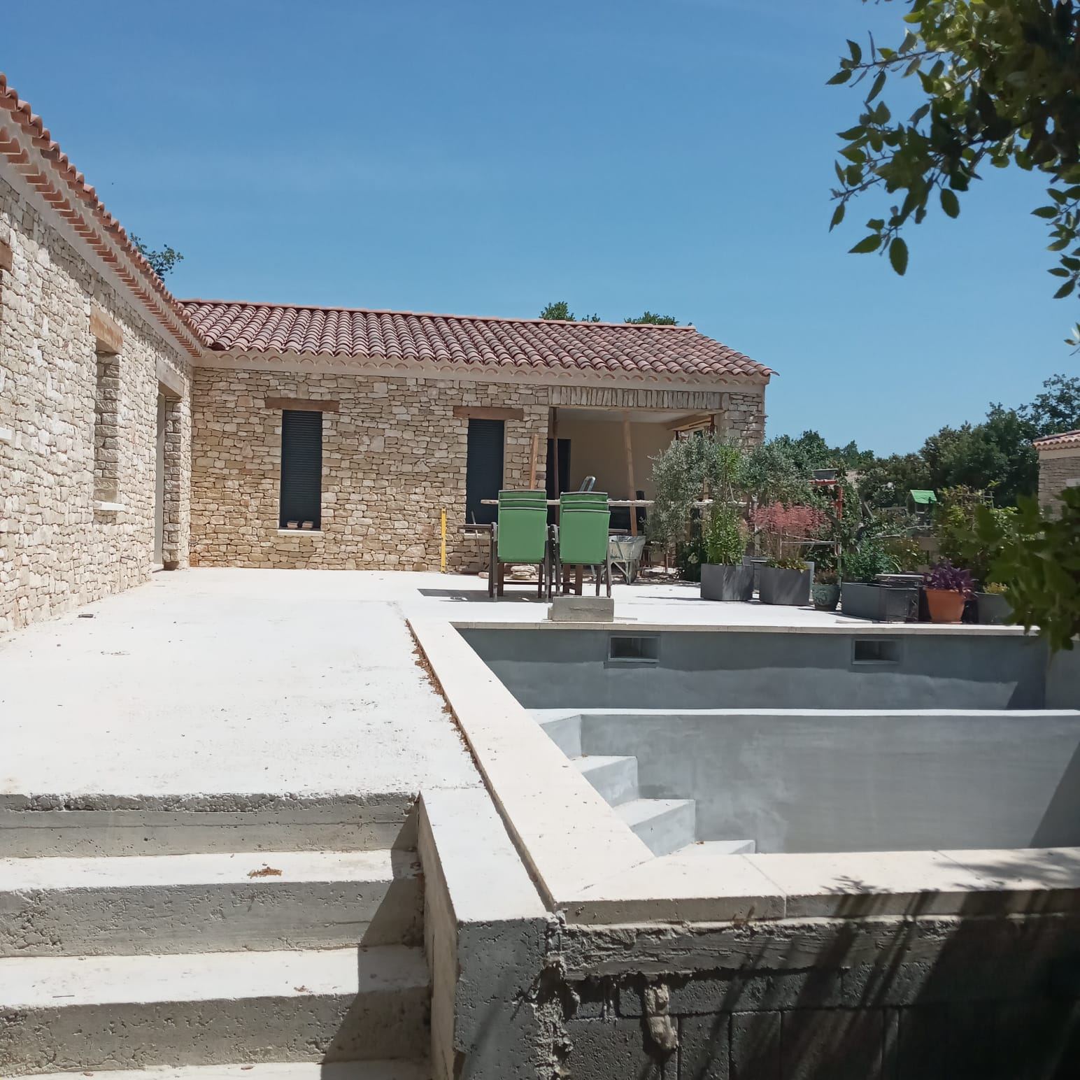 Terrasse en pierre et piscine en cours de finition devant maison en pierre